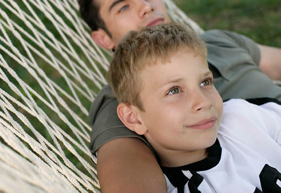 Junge liegt mit seinem Vater in der Hängematte